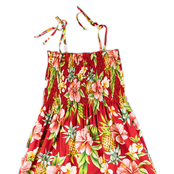 Red smocked top dress with spaghetti straps and designed with pineapples, hibiscus and green leaves print.