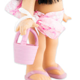 Close-up of the bottom half of the doll holding a pink bag as well as showing her sandals