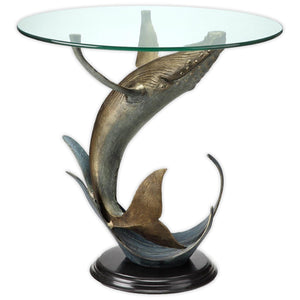 A Modern end table with a scene of a breaching dolphin and water. Made of brass and glass.
