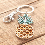 Del-Sol-Color-changing Metal Pineapple Keychain lying on a wooden surface.