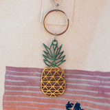 Del-Sol-Color-changing-Metal-Pineapple-Keychain against a fabric background.