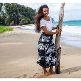 Women on a beach wearing a black and white sarong wrap with flowers
