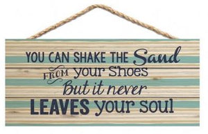 Faux Wood Sign that hangs and reads "You Can Shake The Sand From Your Shoes But It Never Leaves Your Soul"